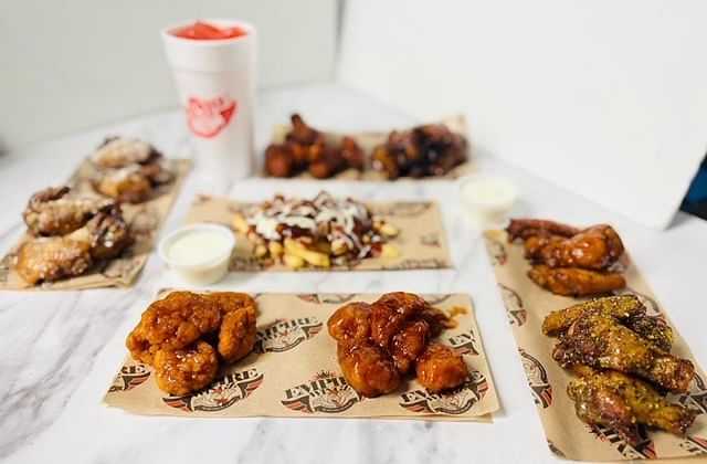 Assorted chicken wings with sauces on a counter.